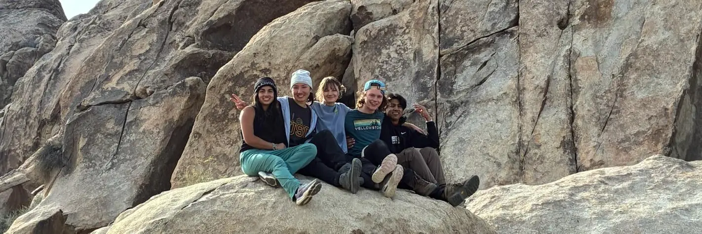 Five MCA members sitting together among large boulders