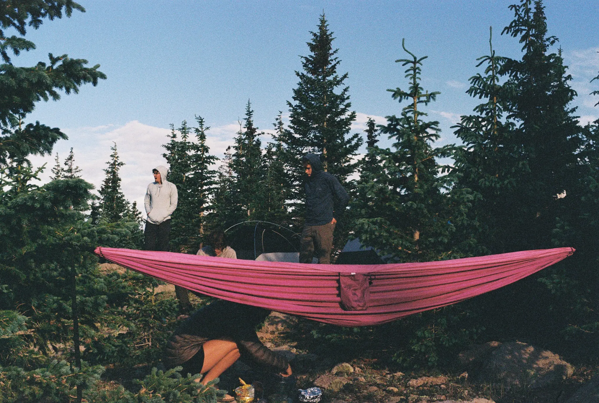 MCA members relaxing in a pink hammock among pine trees